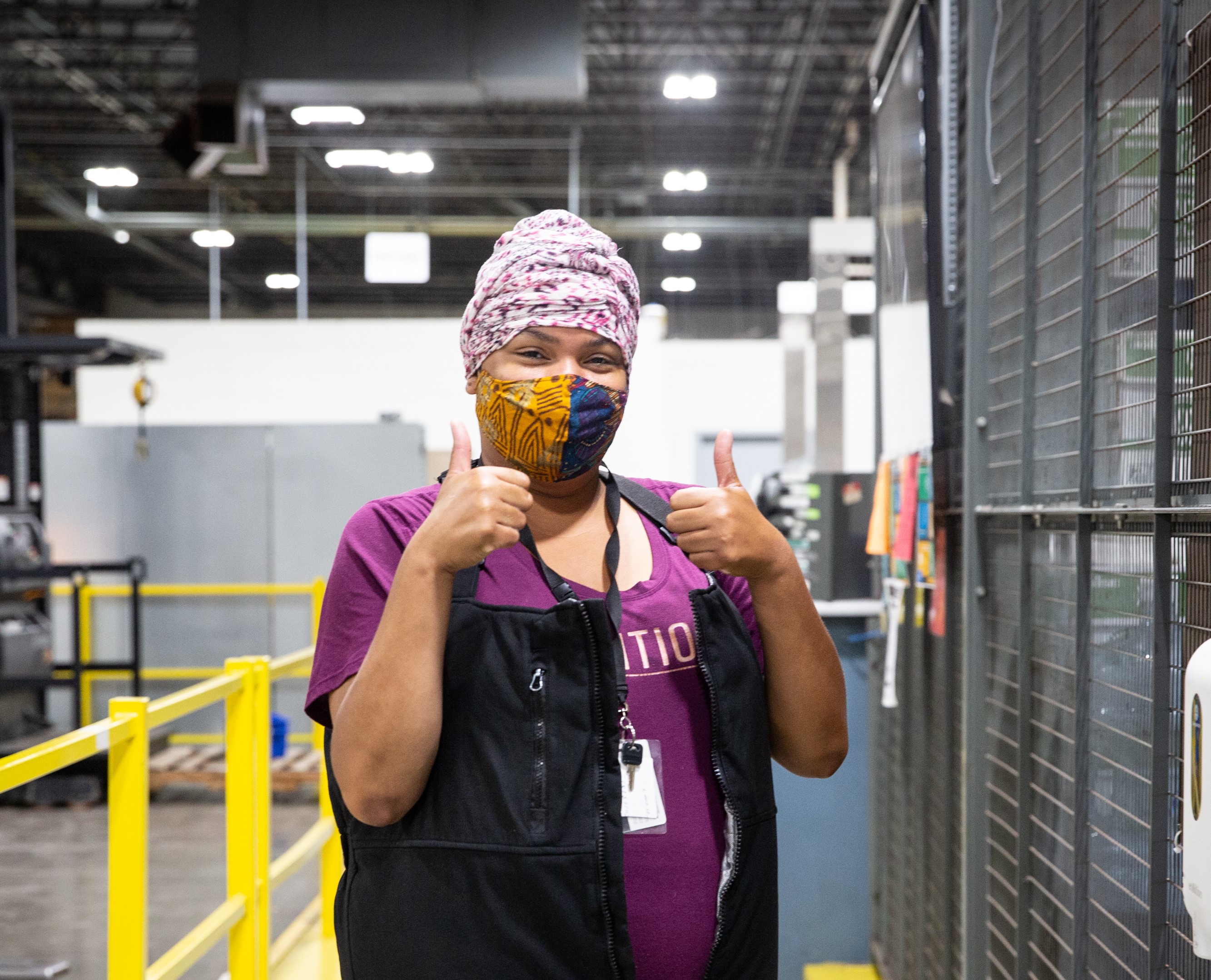 An employee giving two thumbs up in a company facility