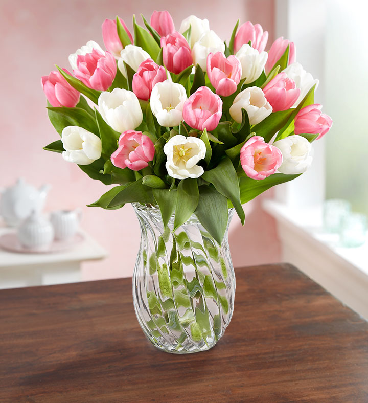 A bouquet of pink and white 1-800-Flowers.com Sweet Spring Tulips in a glass vase on a wooden table