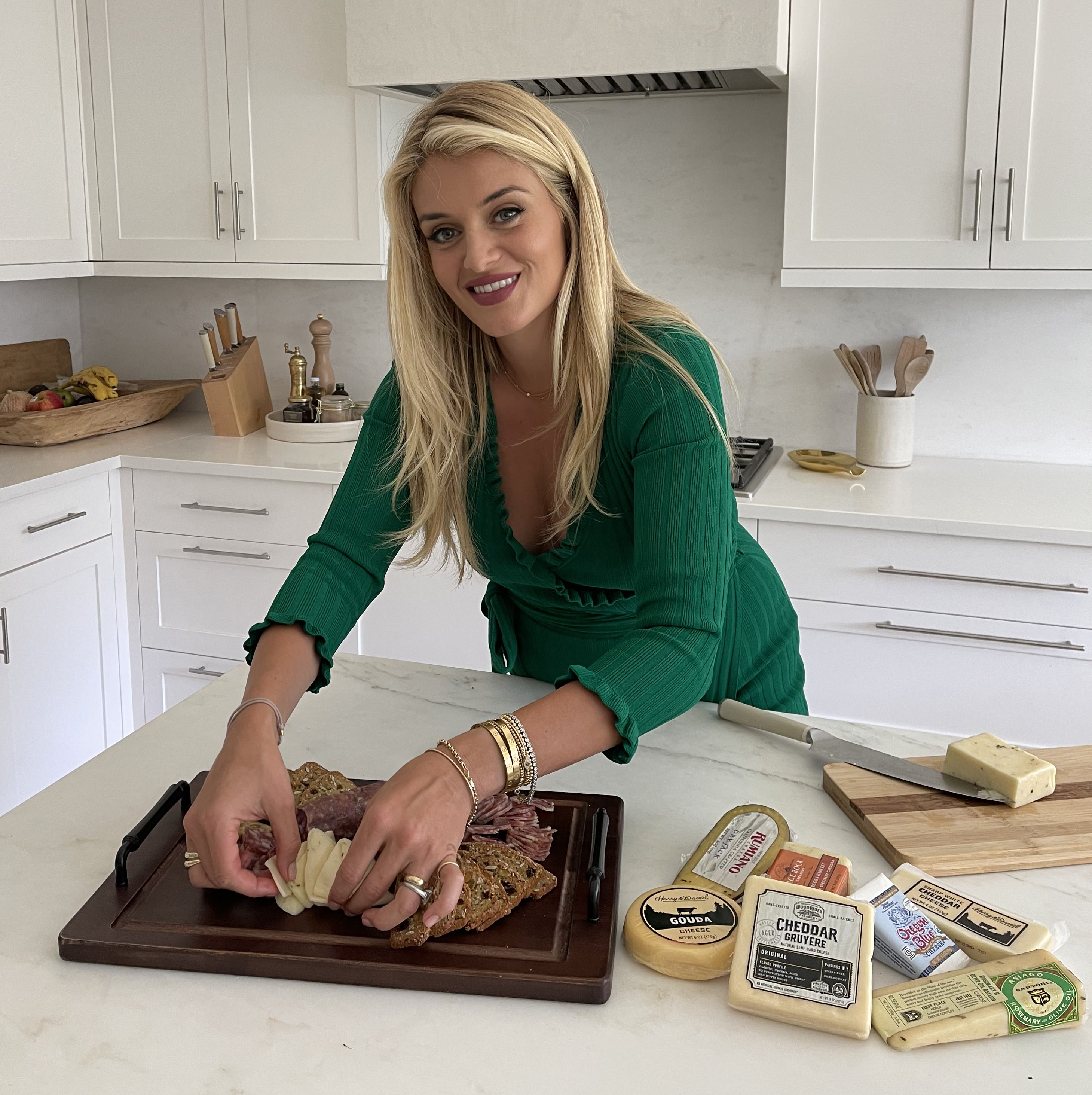 Chef Daphne Oz arranging a charcuterie board in a kitchen with cheese from Harry and David