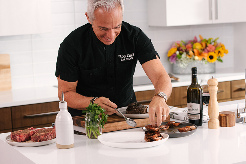 Chef Geoffrey Zakarian preparing a plate of steak and seafood in a kitchen using products from Harry & David