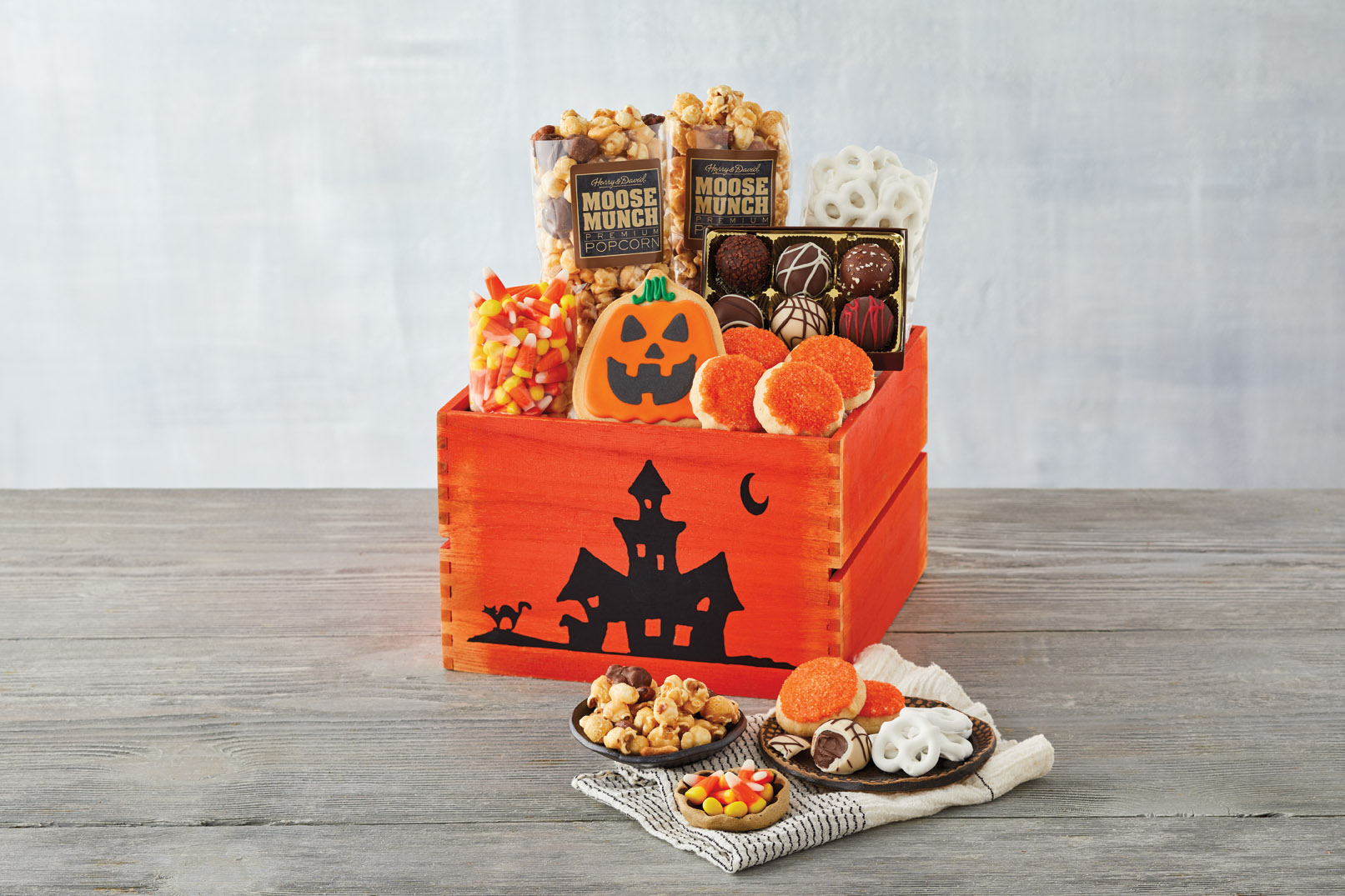 An orange Harry & David Classic Halloween Gift Crate with candy, popcorn, cookies, and chocolate covered pretzels