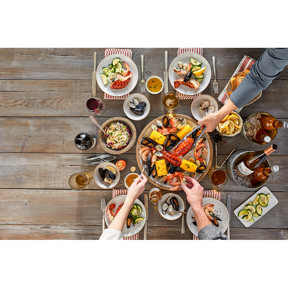 A overhead shot of a table with a variety of seafood from Vital Choice, and the hands of three people serving themselves 