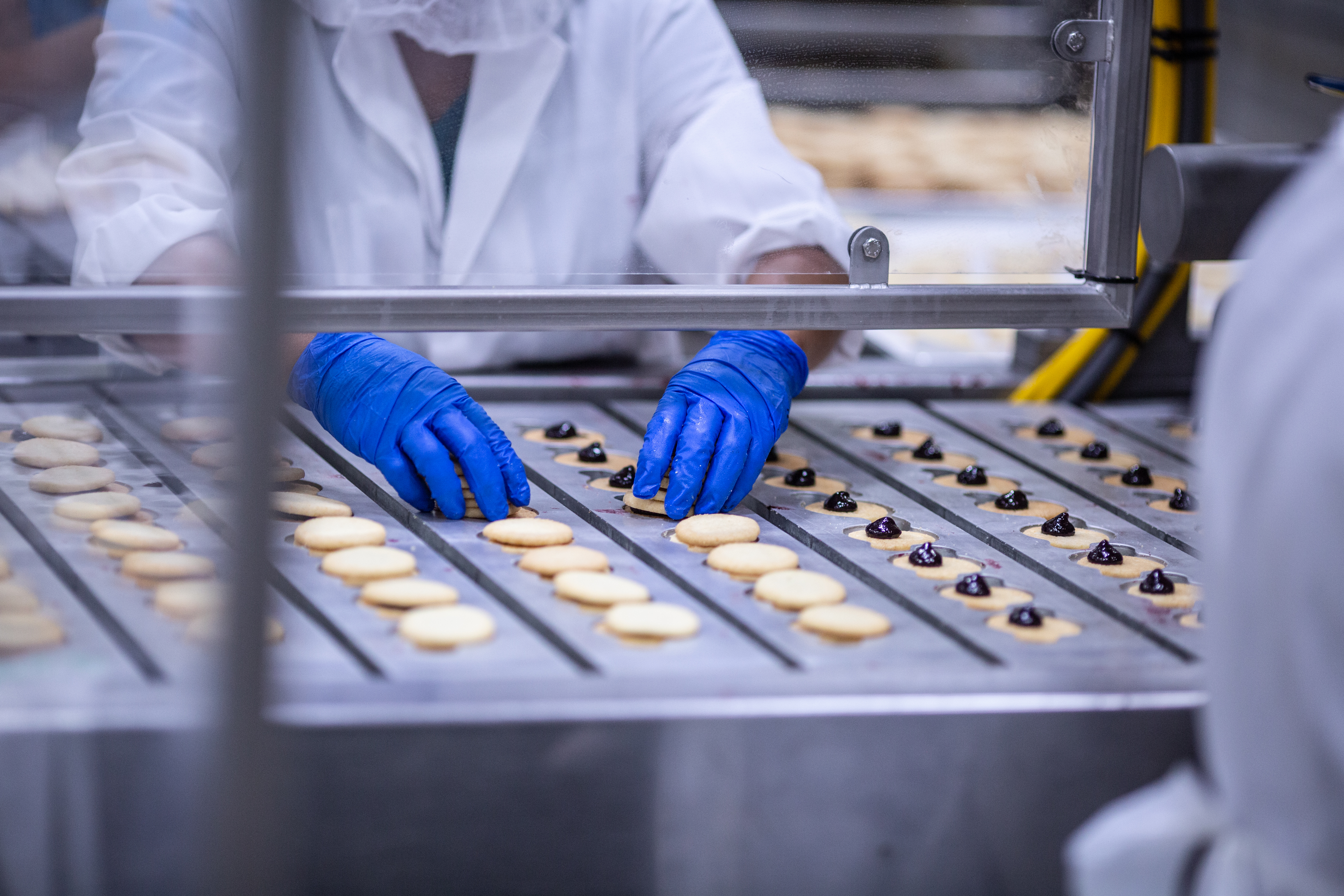 Gloved hands placing cookies on top of their filling to make cookie sandwiches at the Harry and David bakery