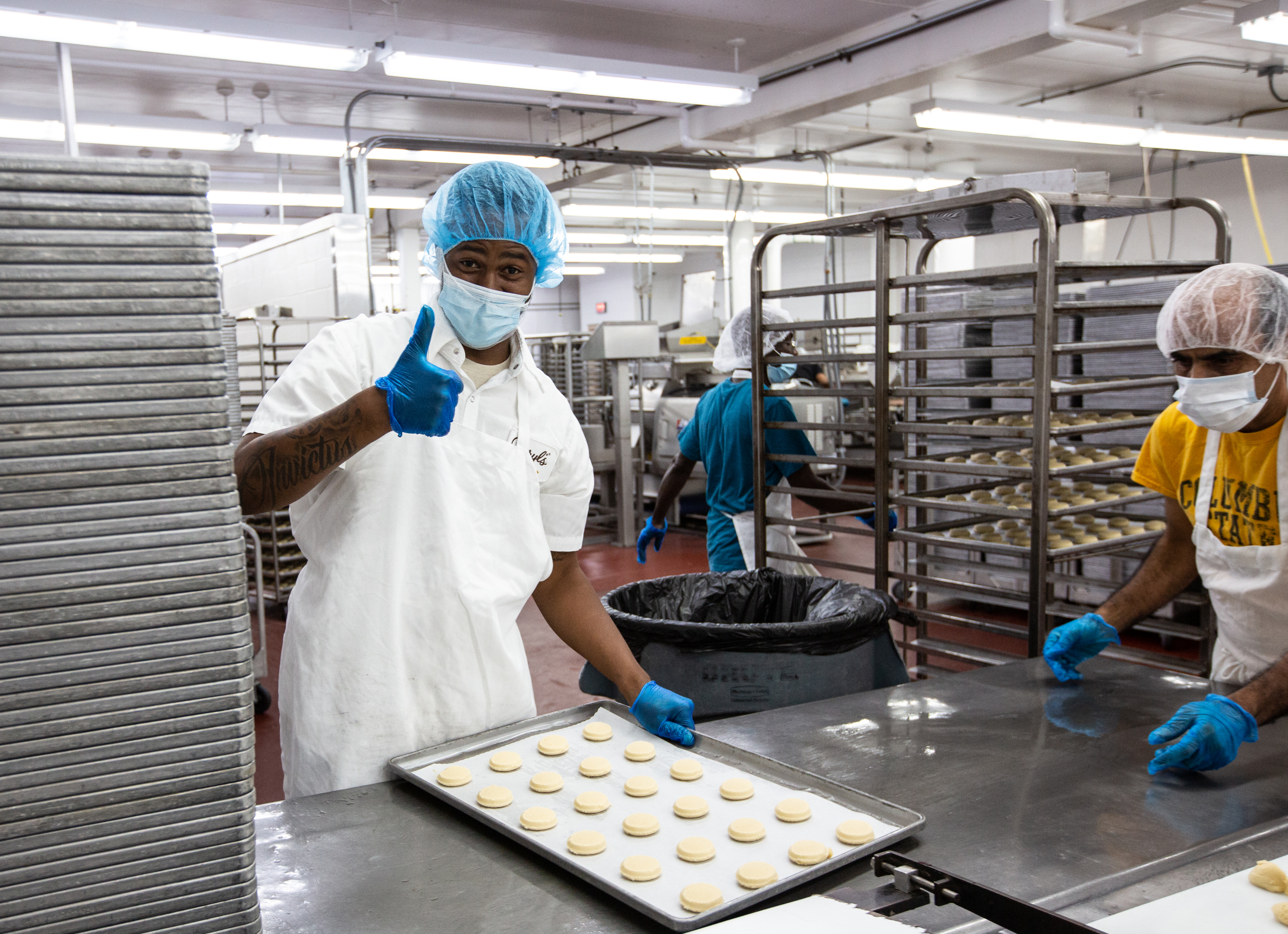 A Cheryl's Cookies associate giving a thumbs up while making cookies 