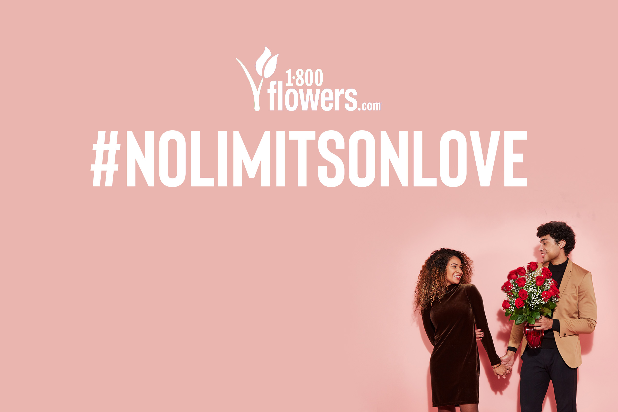 A couple holding hands while also holding a bouquet of red roses under the logo for 1-800-Flowers.com and #NoLimitsOnLove