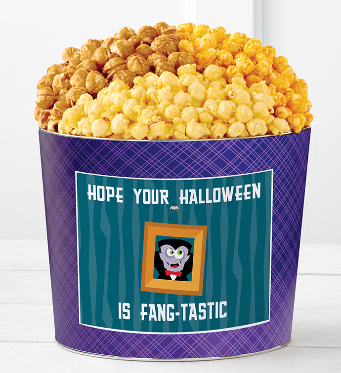 A purple tin of three flavors of popcorn from The Popcorn Factory that says "Hope Your Halloween Is Fang-Tastic" with a cartoon vampire 