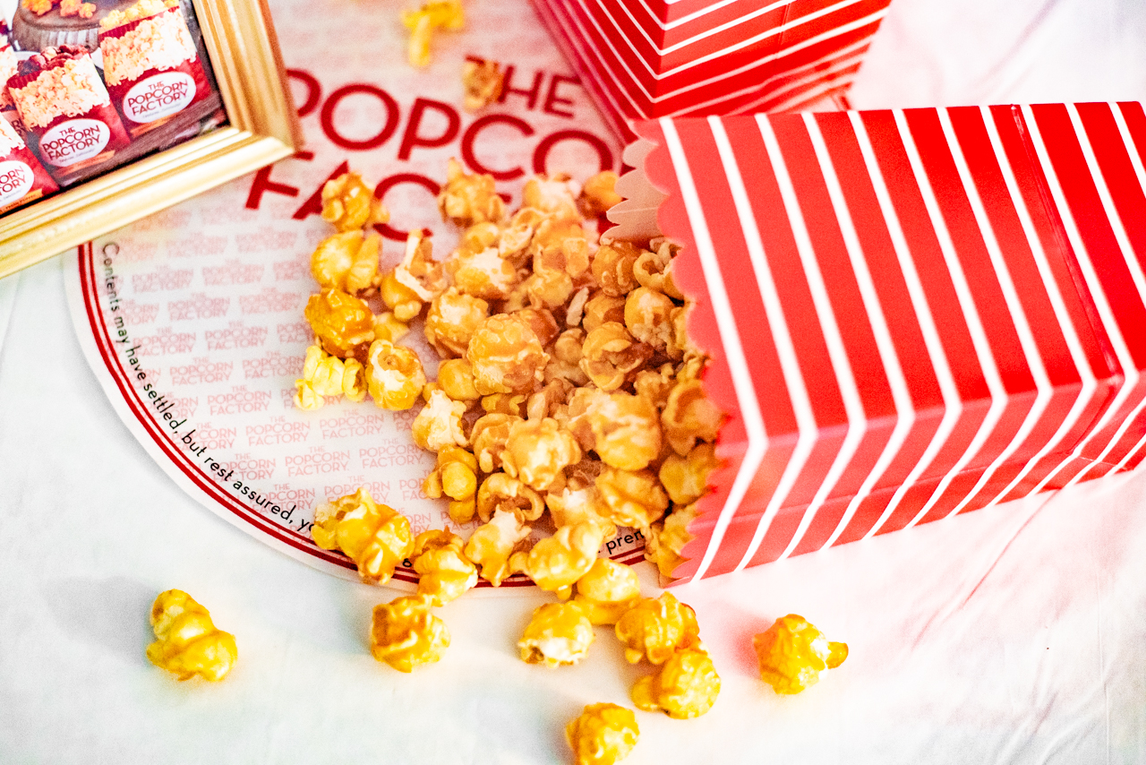A bag of popcorn spilling over onto a placement with The Popcorn Factory logo