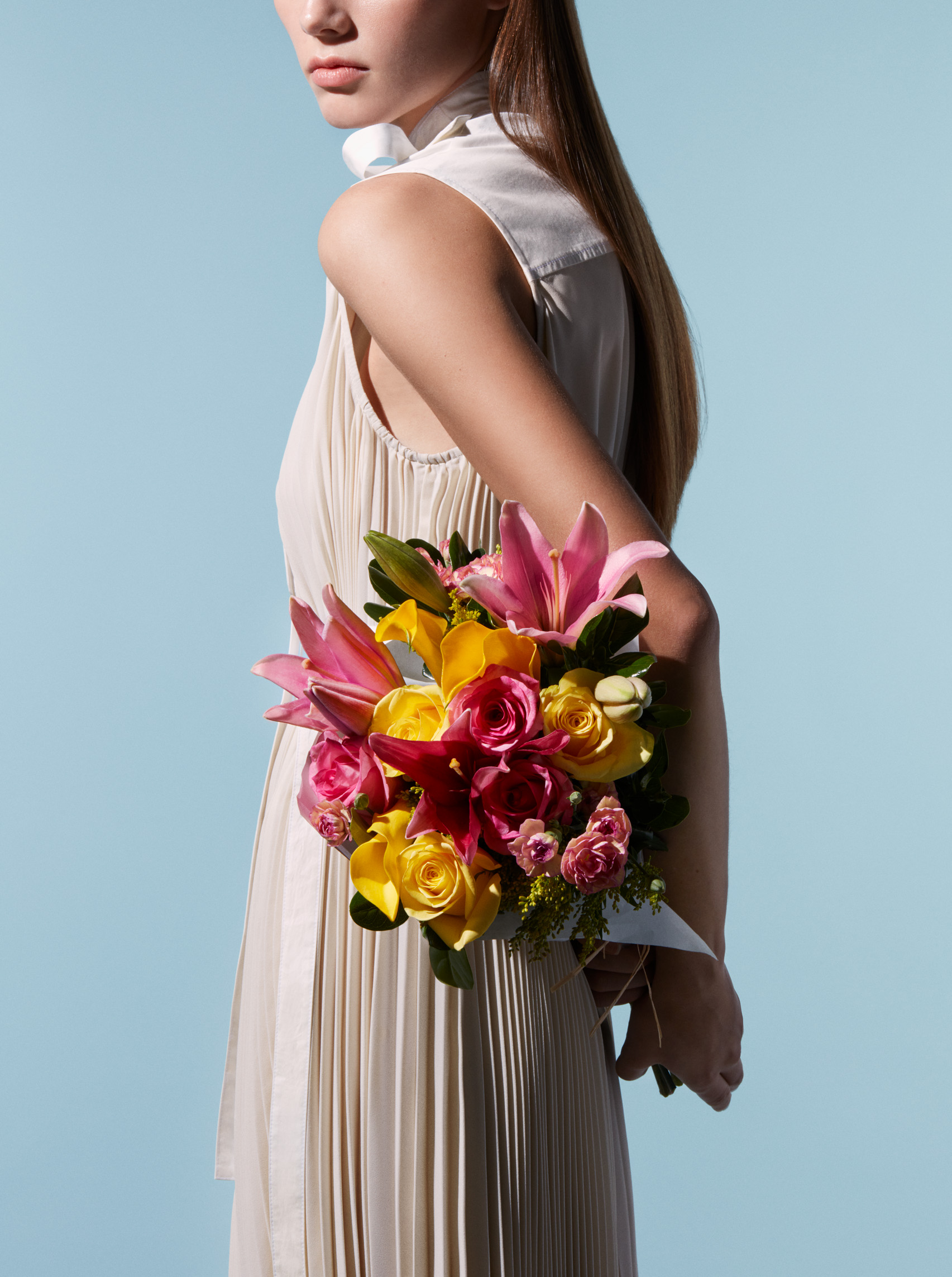 A woman in a cream, pleated dress holding a colorful Watercolor Chiffon Bouquet as part of the Jason Wu for Wild Beauty collection