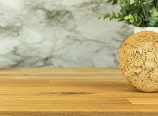 A chocolate chip cookie rolling across a wooden countertop