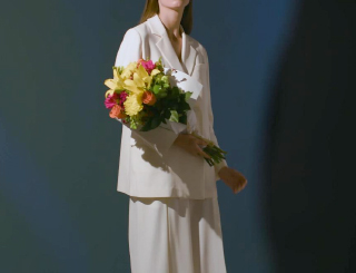 A woman in a white suite holding a colorful bouquet from the Jason Wu for Wild Beauty collection