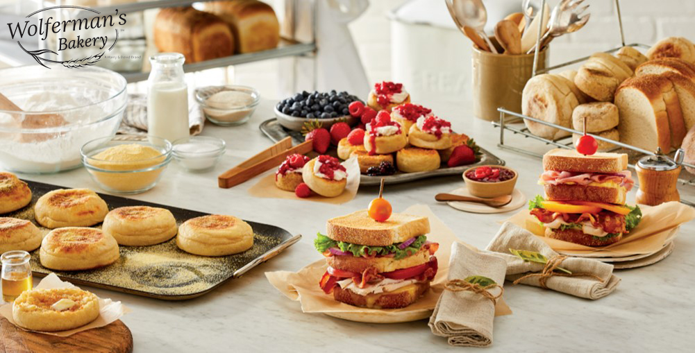 A variety of Wolferman's Bakery products on a counter with fruit and sandwiches 