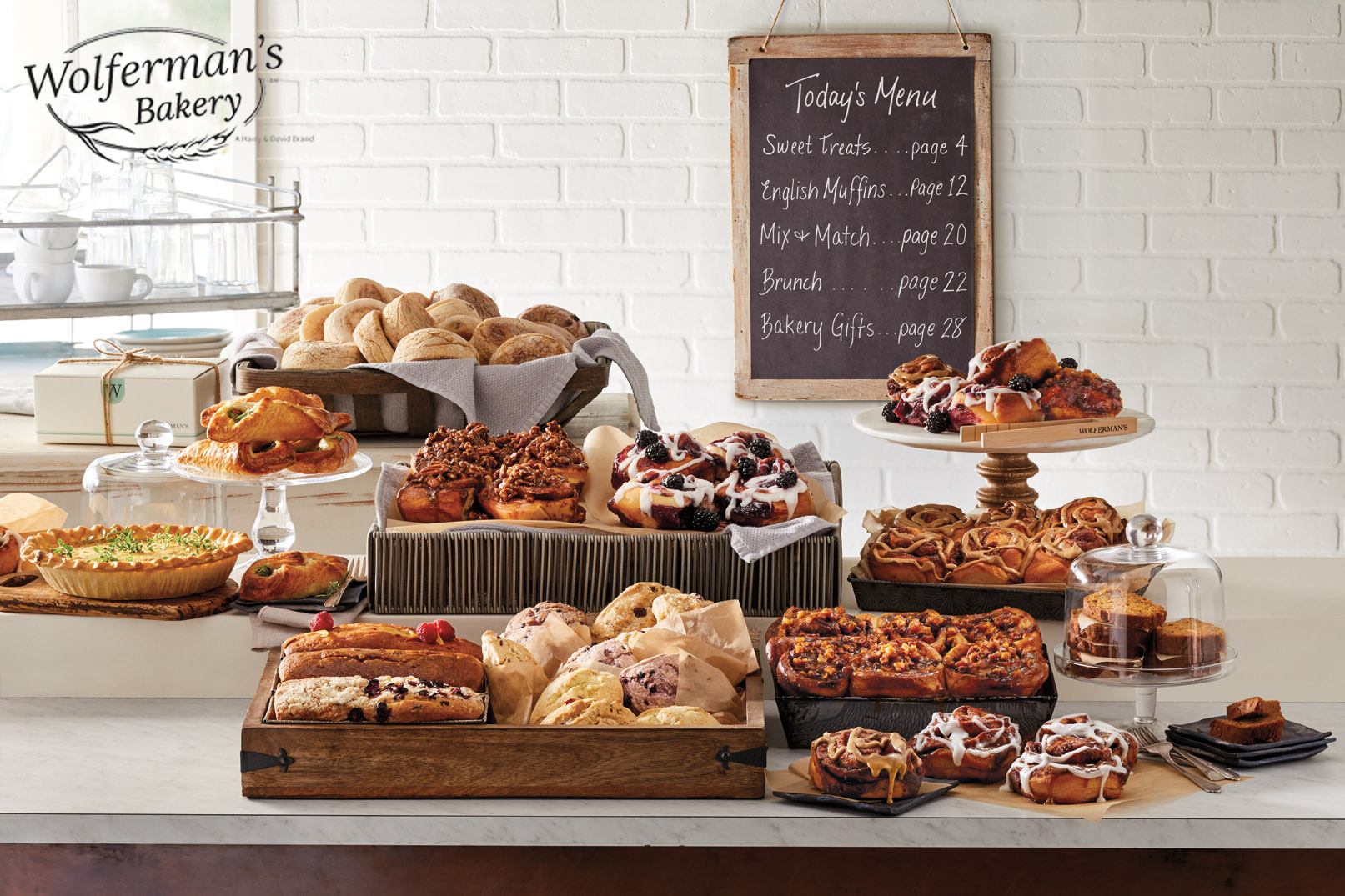 A variety of Wolferman's Bakery products arranged on a store display counter with a chalkboard in the background listing the day's menu