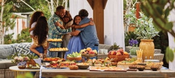 A family enjoying an outdoor celebration with a table full of food from Harry & David