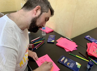 An employee drawing a colorful and bright greeting card as a part the 1-800-Flowers.com Inc Summer of a Million Smiles program