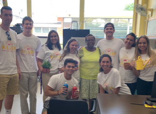 A group of employees volunteering at a school as part of the 1-800-Flowers.com Inc Summer of a Million Smiles program, holding paint and plantings