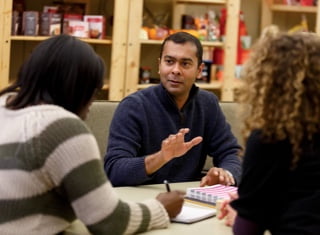 Three employees in meeting at a table, talking and taking notes