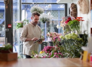 A florist taking inventory of flowers at the front of the shop