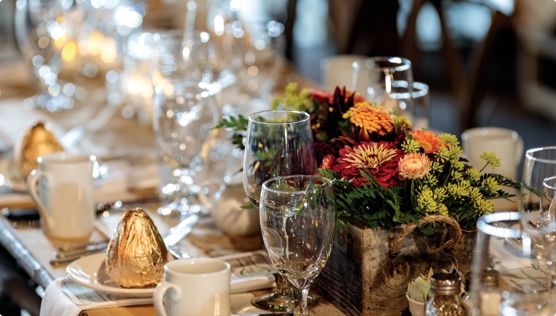 A Harry & David hosted dinner with a table of decorative flowers, Harry & David gold-wrapped pears, and place settings 