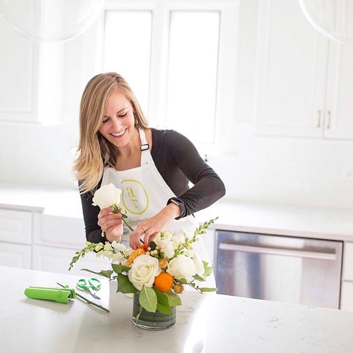 An Alice's Table floral expert making a bouquet on a white kitchen counter
